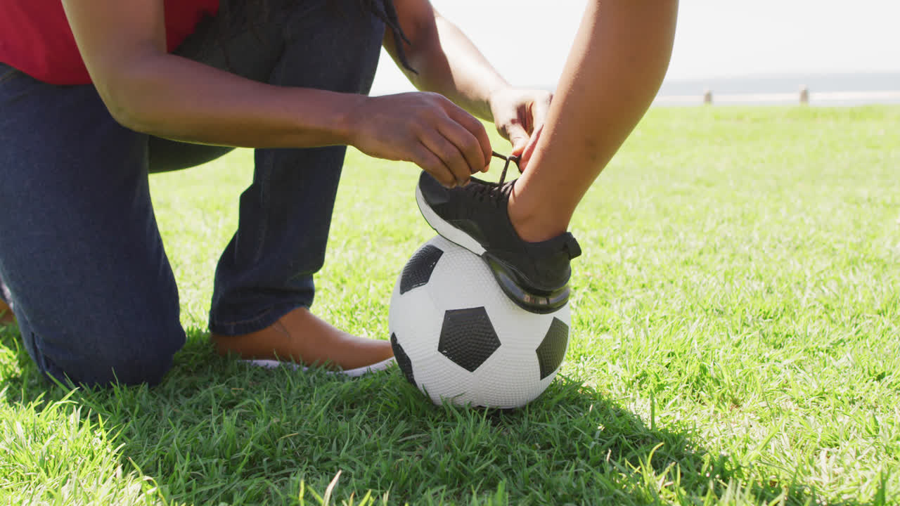 video de la sección media de un padre afroamericano atando un zapato a su hijo