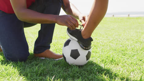 Video-of-midsection-of-african-american-father-tying-shoe-to-his-son