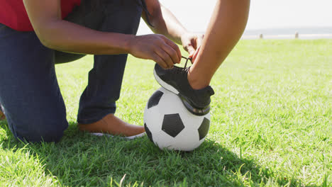 video of midsection of african american father tying shoe to his son