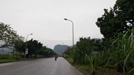 motorbikes, cars, and pedestrians on a scenic road