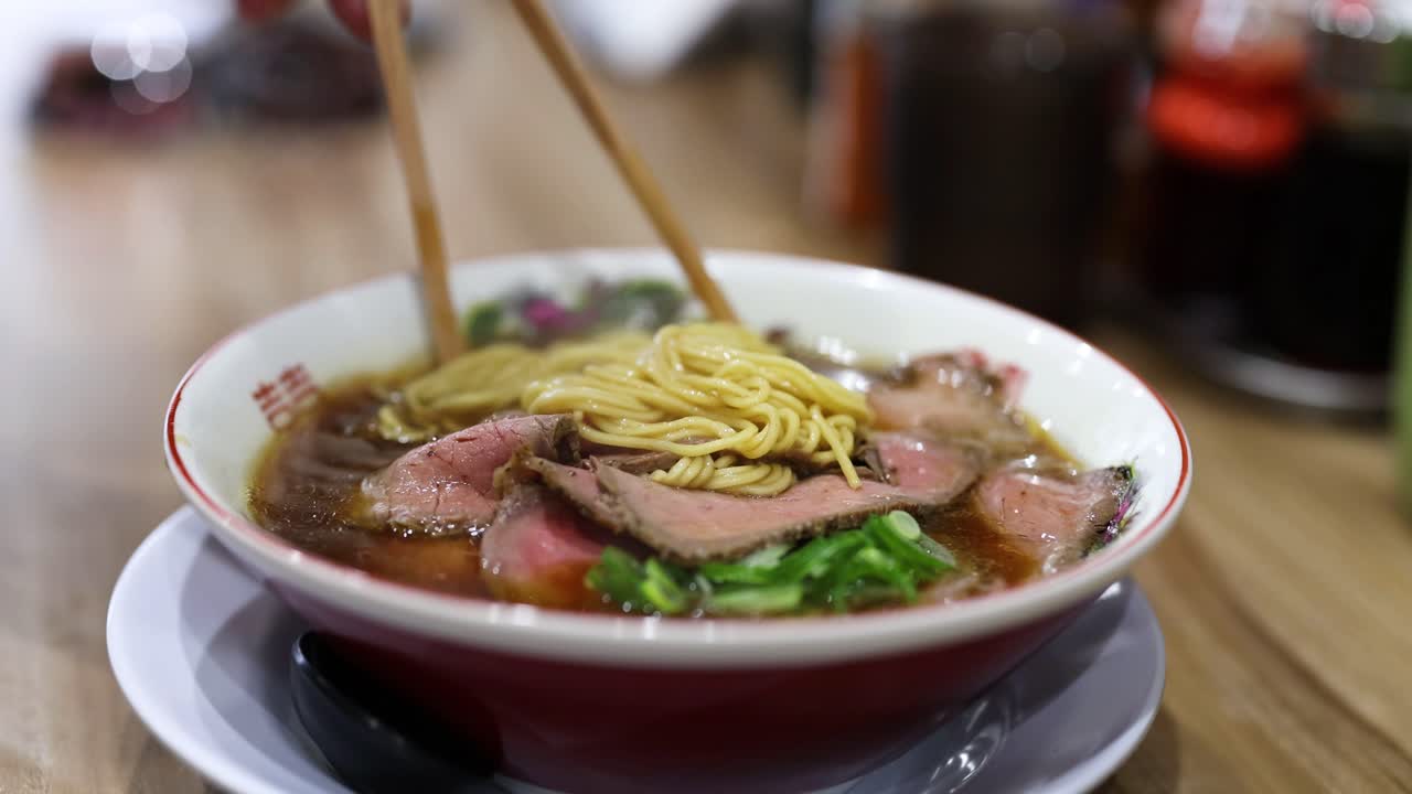 persona comiendo ramen con palillos en un restaurante