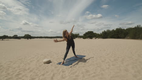 woman practicing yoga exercises in sand dunes and doing triangle poses