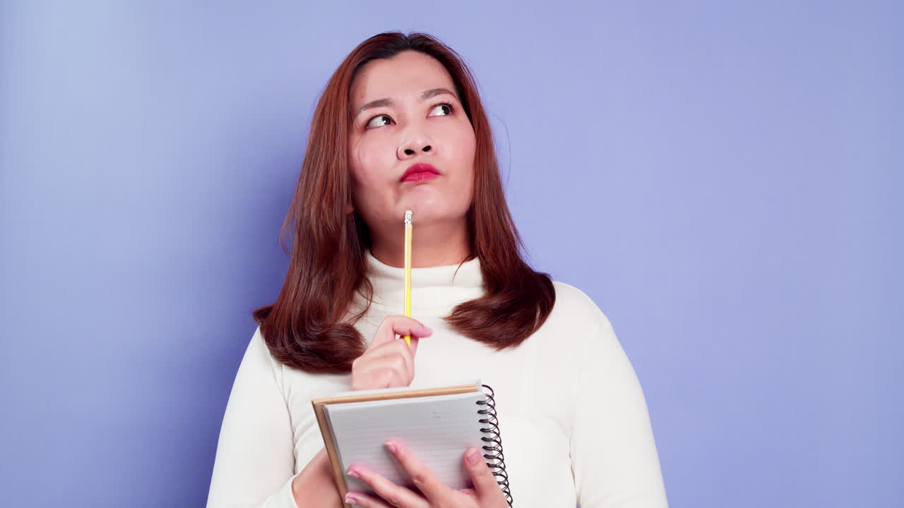 mujer de negocios secretaria asiática sosteniendo un cuaderno y pensando con una estrategia de inspiración de lista para el éxito en el fondo morado
