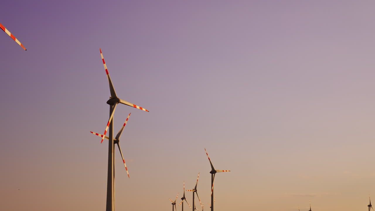 Wind turbines stand tall at sunset. Tall wind turbines tower against a colorful sunset sky, symbolizing renewable energy and sustainable power solutions
