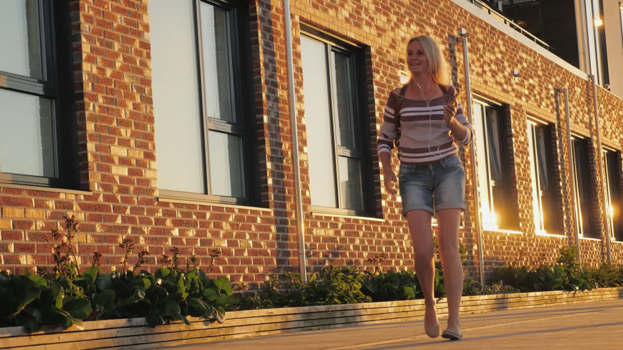 una mujer baila divertidamente alrededor de un edificio de ladrillos video 4k