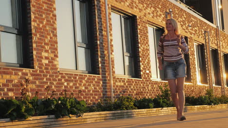 a woman dances amusingly around a brick building 4k video