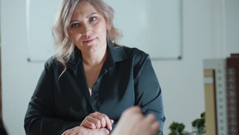 lady listening to business expert during presentation in office while seated across desk with miniature building model in view showing engaged and focused expression