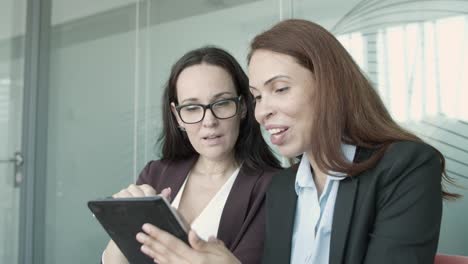 two caucasian businesswomen watching presentation via tablet