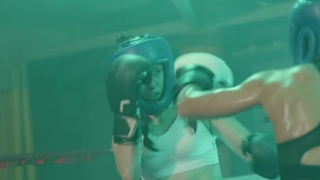 two female boxers in helmets and boxing gloves training in ring