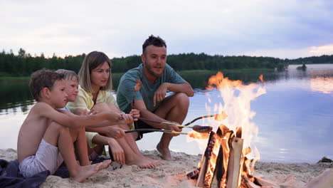 family eating sausages on the beach