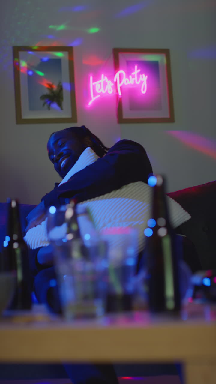 video vertical de un hombre borracho sentado en el sofá bebiendo alcohol en la fiesta de la casa 1