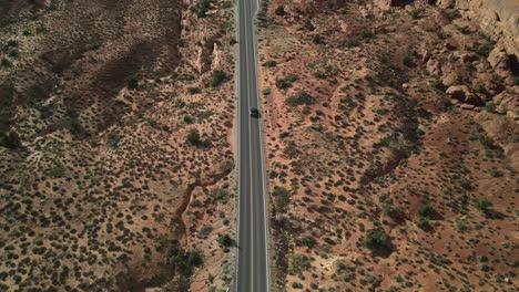 Vista-Aérea-Del-Parque-Nacional-Arches-Con-Una-Carretera-Y-Un-Automóvil-Convertible-Que-Viaja-En-El-Medio