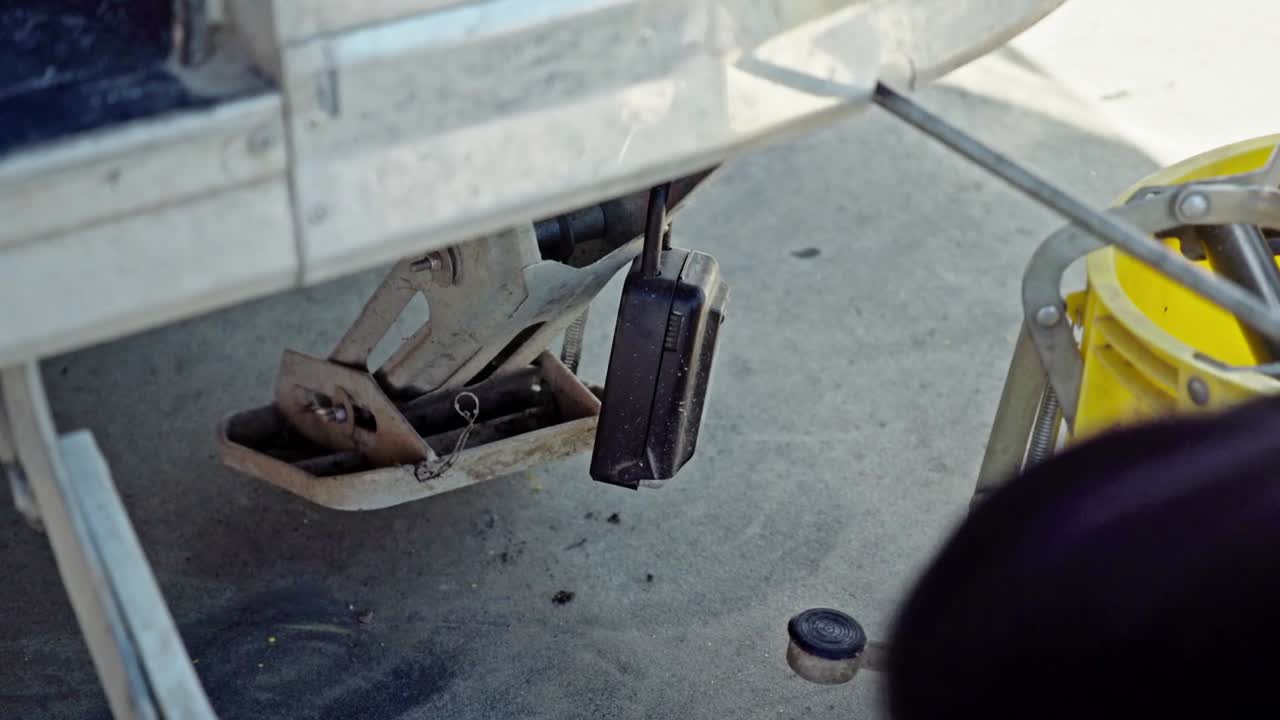 A worker winding up a stabiliser leg on a mobile coffee cart, retracting the support before moving, closeup. Early morning industrial setup with practical hands-on workflow
