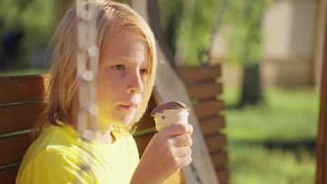 boy eating chocolate ice cream on a swing