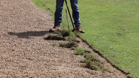 person meticulously trimming grass edge with shears.