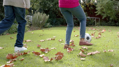 midsection of african american mother and son playing football in garden, in slow motion