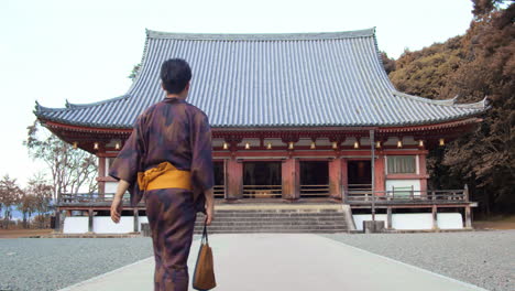 guy wearing a yukata walking towards a temple to go pray in kyoto, japan soft lighting