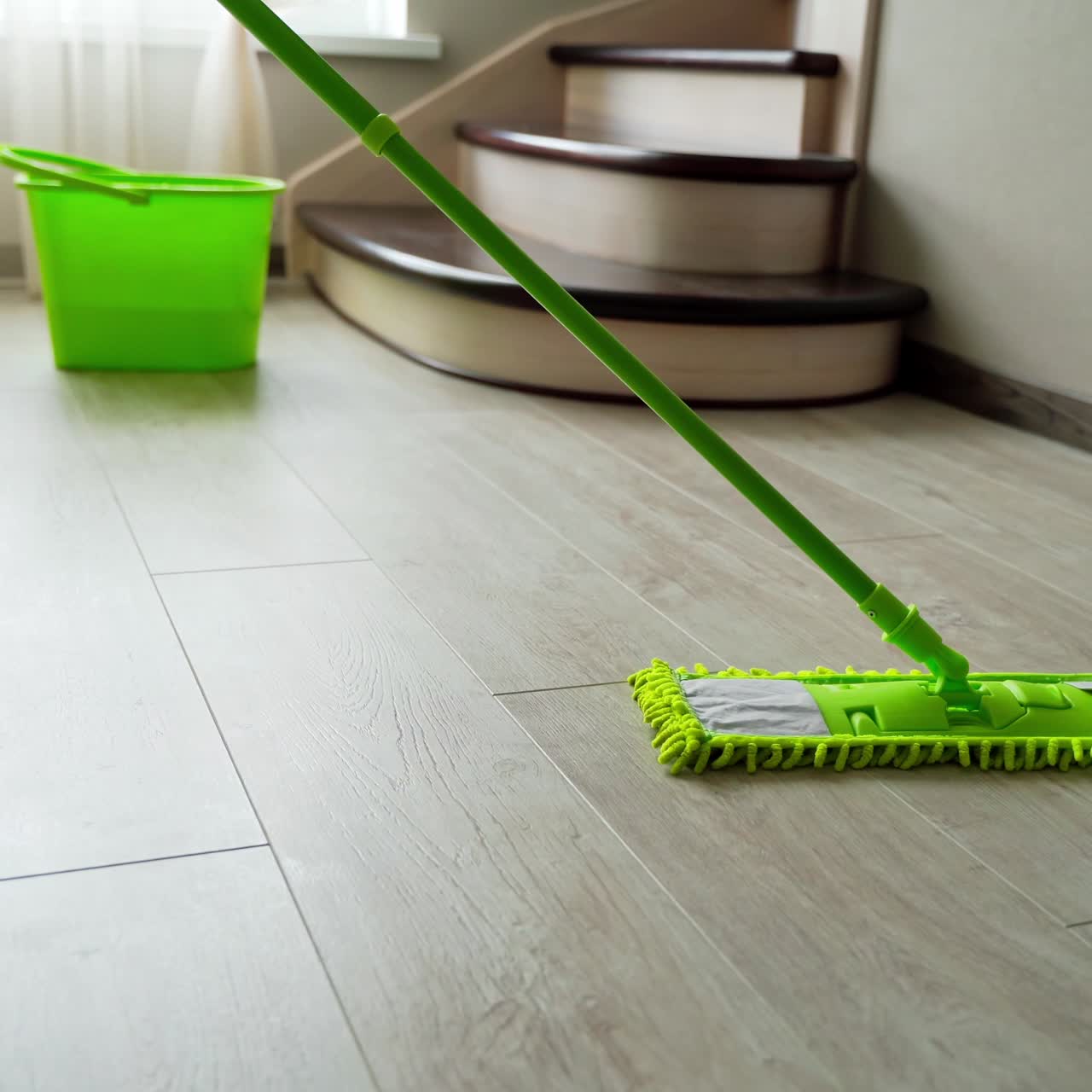 Washing the laminate floor with a mop. Housekeeper with mop and bucket is cleaning floor at home. Floor care concept.