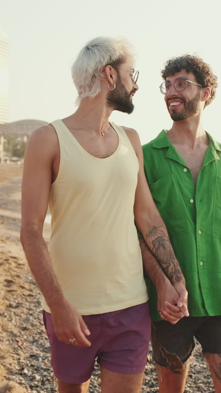 Coppia gay felice che cammina mano nella mano sulla spiaggia