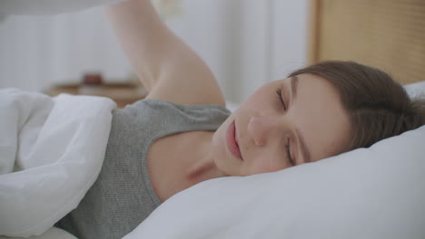 la mujer se despierta, se levanta, estira las manos en la cama, se siente saludable.