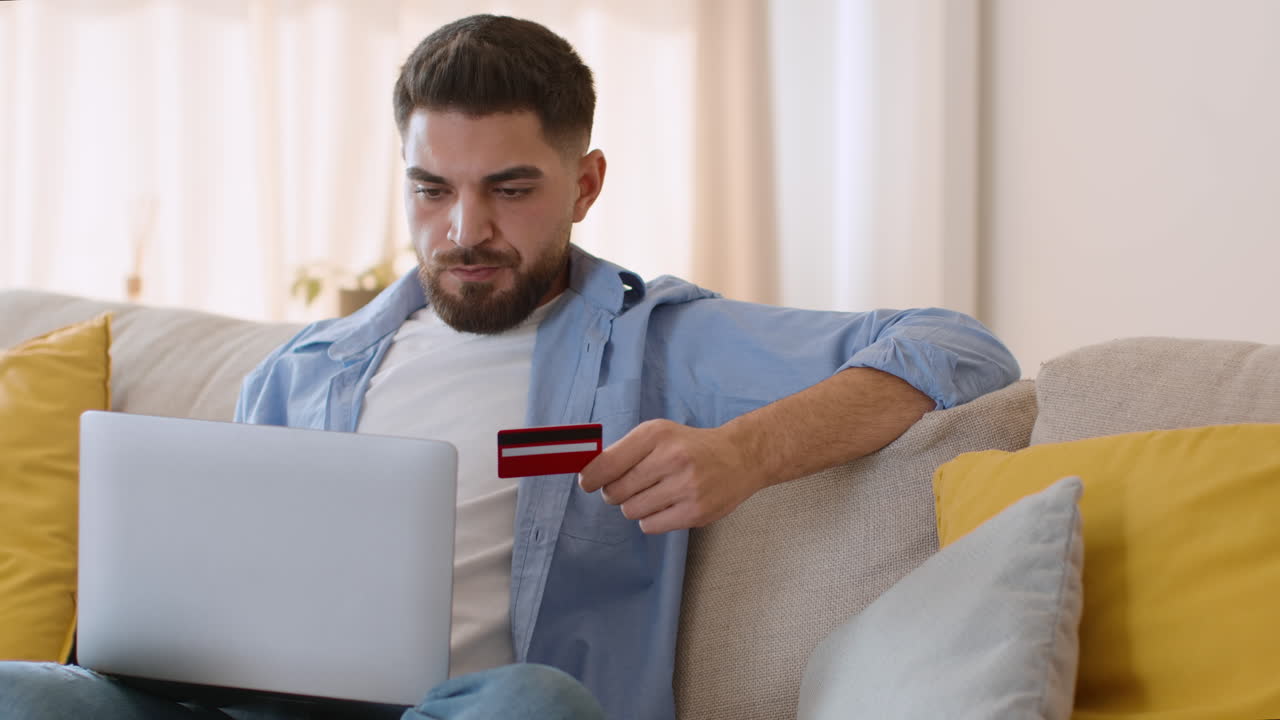 Uomo che usa laptop e carta di credito per lo shopping online a casa