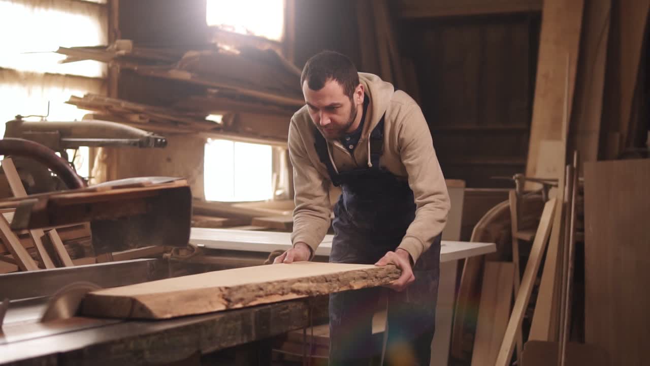 кавказский мужчина работает в своей мастерской. сосредоточенно пила дерево на и электрической машине