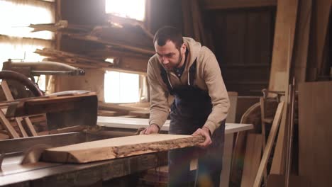 caucasian man is working in his workshop. concentrated sawing a wood on and electric machine