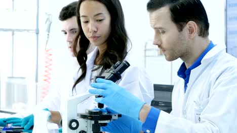 científicos o químicos que utilizan microscopios y otras tecnologías. científicos en equipo trabajando juntos en un laboratorio. resolución de 4k.