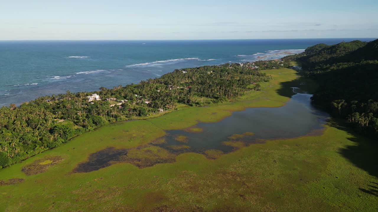 Picturesque aerial drone shot of mangrove swamp waters facing lush island village and coastline during daytime - Virac, Catanduanes, Philippines