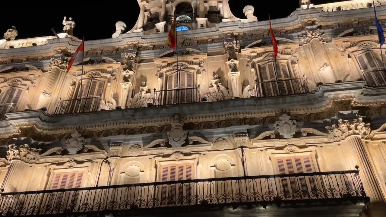 filming of the balcony of the Salamanca town hall integrated into the Plaza Mayor with its spectacular lighting, its flags and the clock tower with the bell appears and we see the black sky
