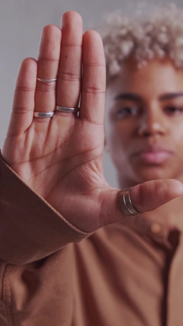 Donna afroamericana seria che mostra un gesto di stop con il palmo aperto della mano.