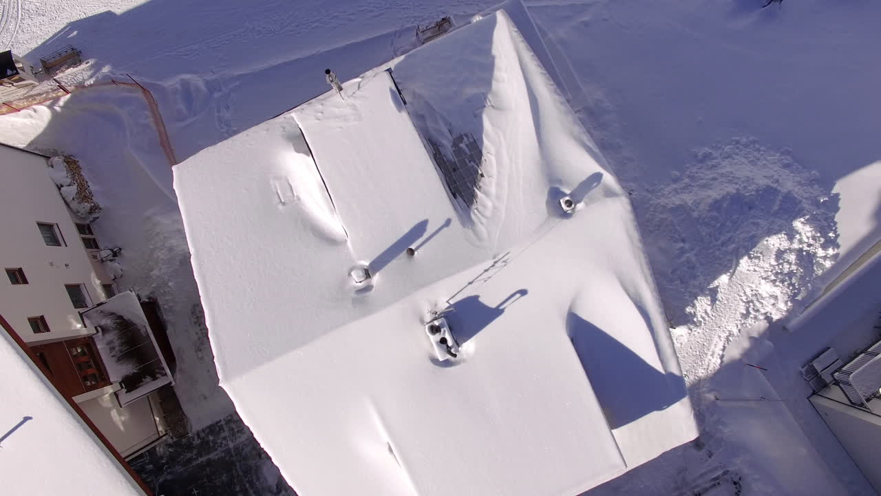 Aerial 4K rotating drone shot rising above a snow covered ski chalet in the Alps