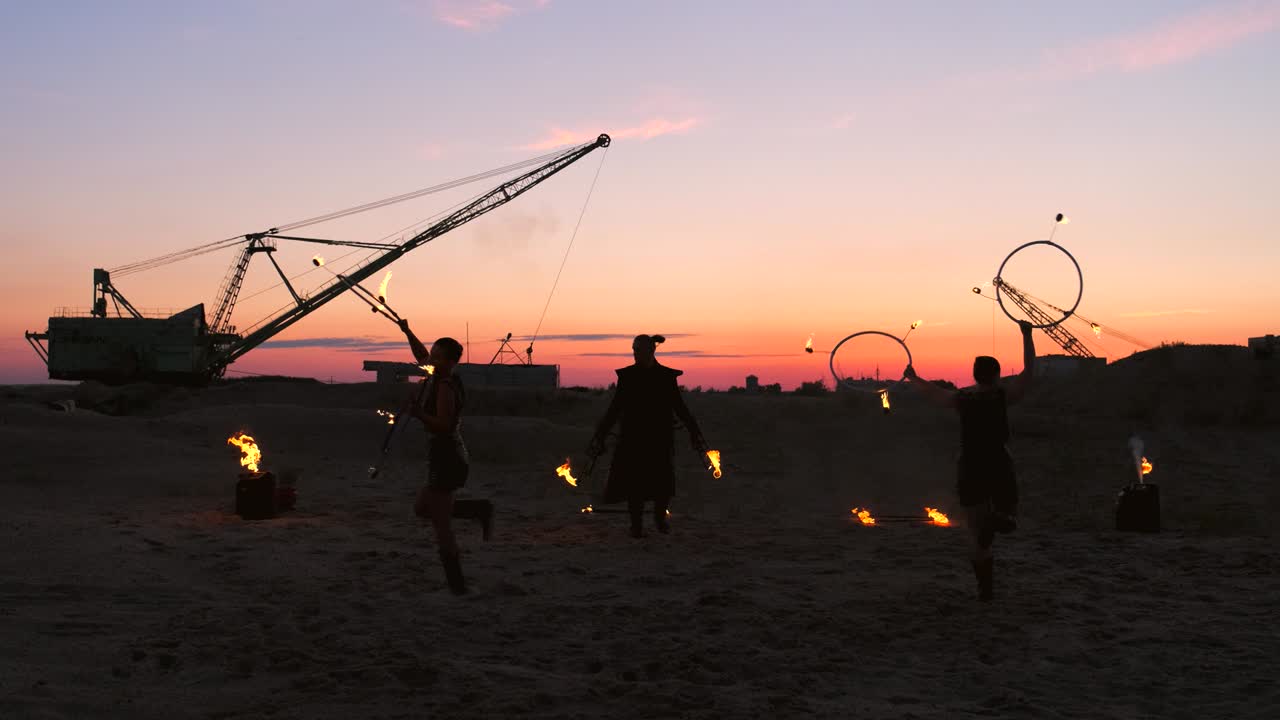 전문적인 서커스 공연자 그룹은 불을 던지고 불꽃을 던지는 물체를 회전시키는 것을 사용하여 느린 동작으로 댄스 쇼를 보여줍니다.