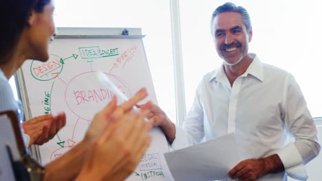 Executives-applauding-their-colleague-while-giving-presentation-on-flipchart-4k