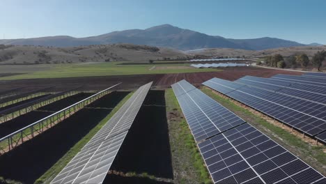 drone over photovoltaic solar panel park farm blue sky fields mountain background