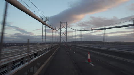 toma en movimiento de un vehículo que cruza un puente de carretera con una maravillosa luz de puesta de sol y nubes en edimburgo, escocia