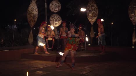 fire performers juggling flaming torches during balinese african rhythm fire dance show at night bali safari and marine park, indonesia - slow motion