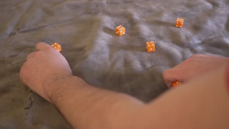 ten orange dice being rolled in slow motion onto a gray felt platform cover