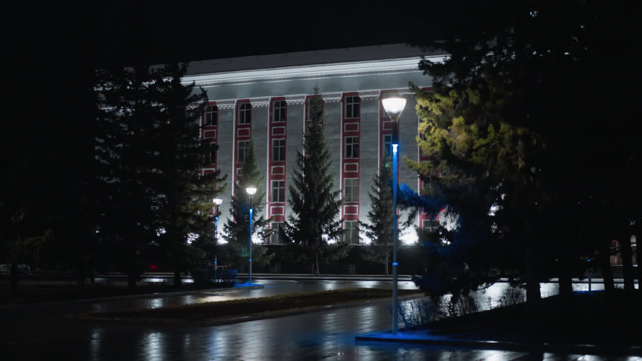 아름답게 조명된 역사적인 건물의 야간 전망, 거리 조명이 주변의 나무와 은 보행로에 빛을 고 있습니다.