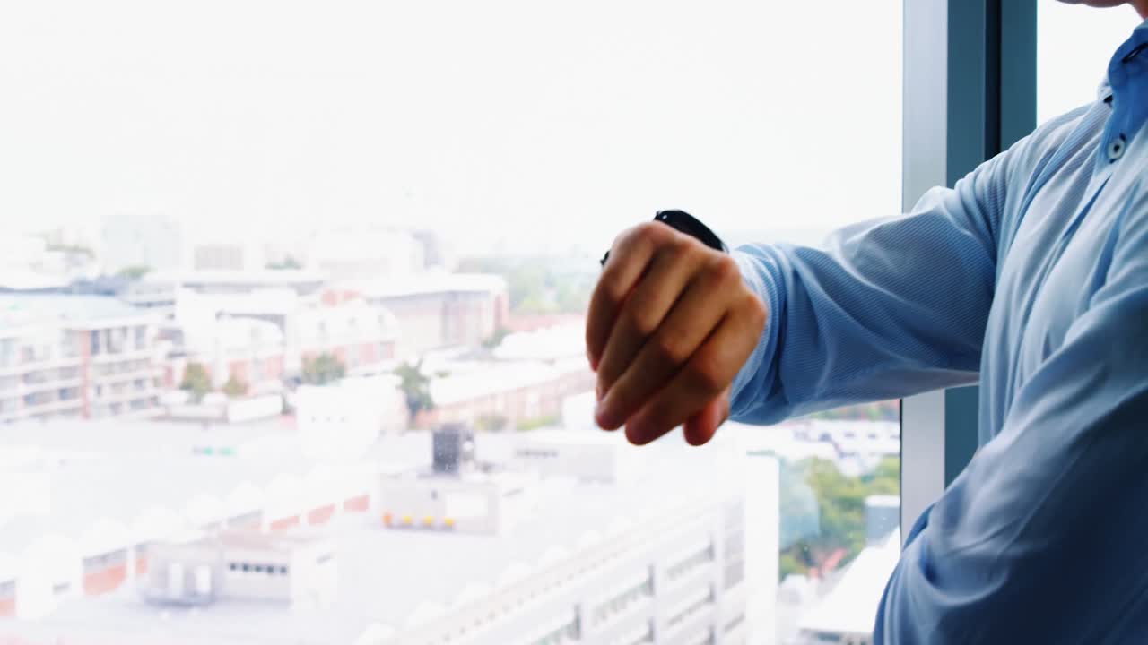 Dirigente che controlla l'ora stando in piedi vicino alla finestra