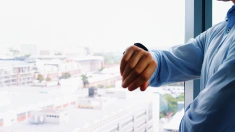 Executive-checking-time-while-standing-near-window