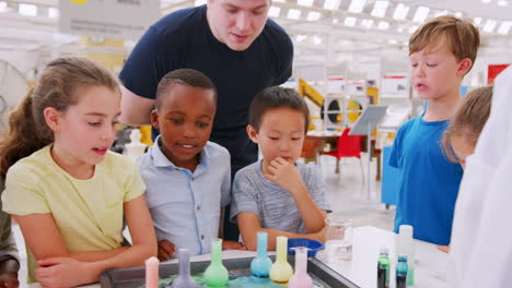 niños y el maestro mirando frascos en el experimento de ciencia