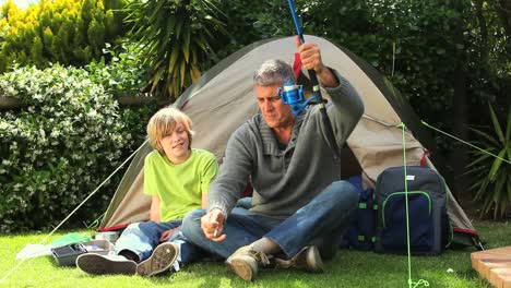 man showing his child how to hang a worm on the hook