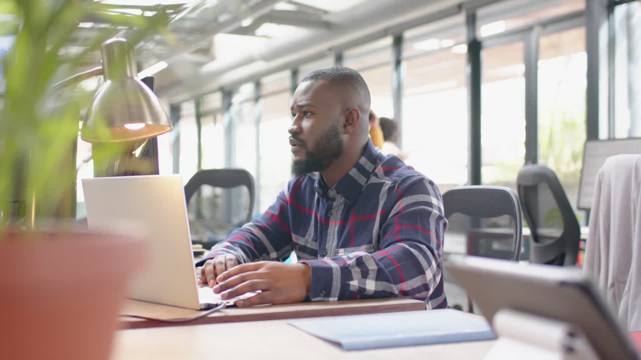 African american man using laptop sitting on his desk at office