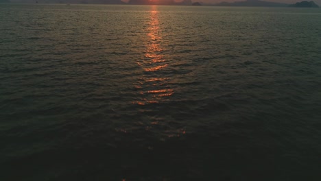 The-Sun-Sets-Over-A-Mountain-Range-And-Expansive-Body-Of-Water-In-Thailand