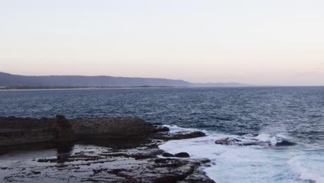 rocky shore during evening and far off mountains in background