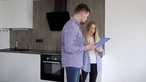 man and woman walking and watching the apartment while holding tablet with documents