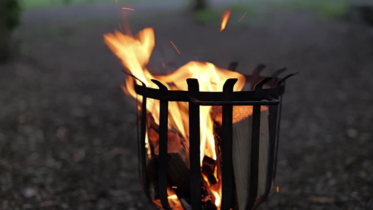Burning wood in fire pit, close-up parallax slider shot in real time, outdoors scene.