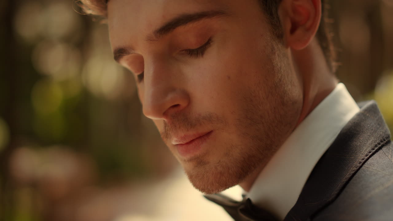 공원에서 카메라를 보는 매력적인 남자. 신랑은 아치  ⁇ 에서 신부를 기다리고 있다