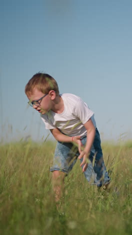 un niño pequeño con una camisa blanca y pantalones vaqueros cortos es capturado a mitad de salto hacia atrás en un campo soleado y cubierto de hierba, mientras su hermano menor, también con una camiseta blanca y shorts, salta alegremente a su lado